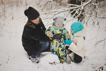 母亲和两个孩子在雪林背景上走动母亲和两个孩子在冬季散步914图片