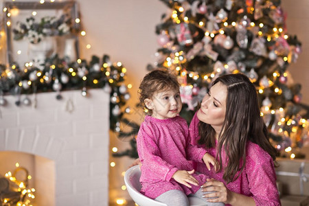母亲的肖像和女儿在圣诞树上闪发光图片