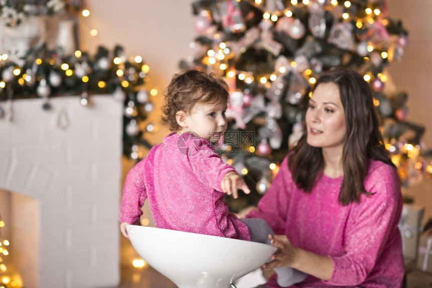 母亲的肖像和女儿在圣诞树上闪发光图片