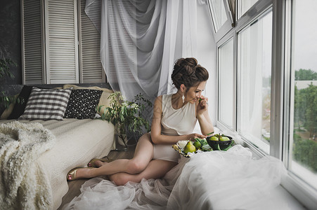 美丽的女孩坐在窗户边吃水果背景图片