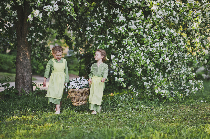 两个女孩拿着一篮花女朋友提了一个柳条篮子里面装着花是用来装饰花园的图片