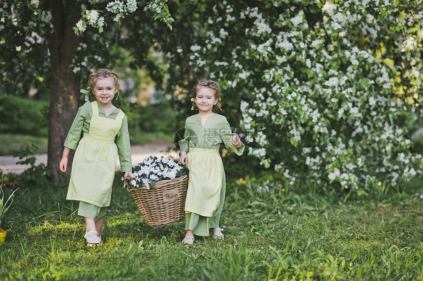 两个女孩拿着一篮花女朋友提了一个柳条篮子里面装着花用来装饰花园图片