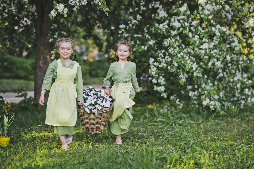 两个女孩拿着一篮花女朋友提了一个柳条篮子里面装着花用于花园装饰图片