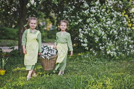 两个女孩拿着一篮花女朋友提着一个柳条篮子篮子里放着花用来装饰花园图片