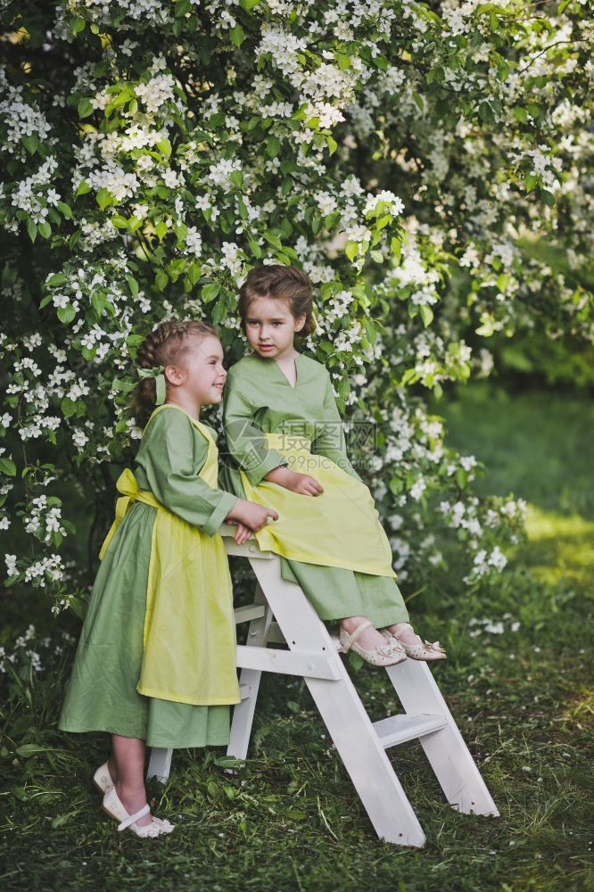 在樱桃果园里玩耍的身穿亚麻布衣儿童图片