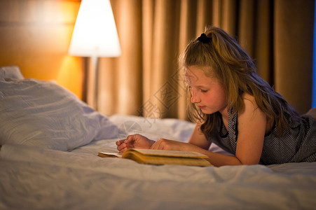 小女孩在灯泡下看书孩子躺在863床上喜欢看书图片