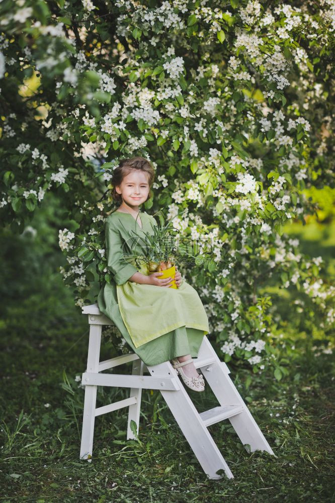 在花园背景的绿裙和围上女孩图片