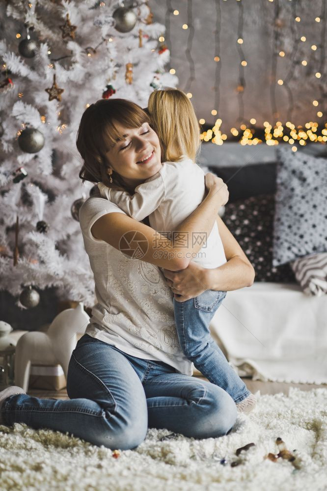 母亲在新年的前夕拥抱着小女儿一个温柔的家庭拥抱着一个母亲和女儿有一个圣诞树7145图片