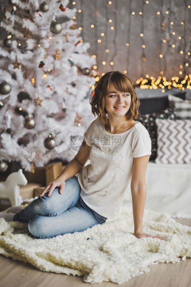 美丽的女孩坐在圣诞树7204附近的地毯上图片