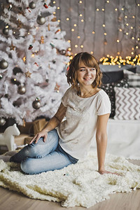 美丽的女孩坐在圣诞树7204附近的地毯上背景图片