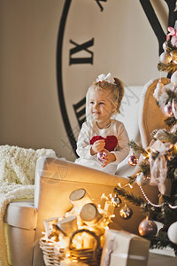 在一棵大圣诞树和拨号的铃声面前婴儿肖像图片