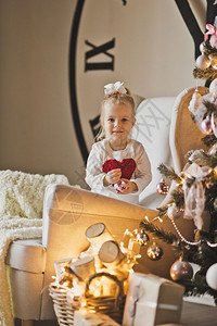 在一棵大圣诞树和拨号的铃声面前婴儿肖像图片