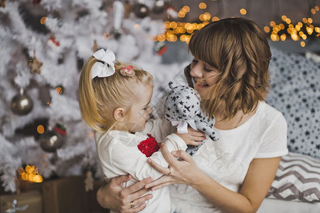 年轻母亲在圣诞节前温柔地拥抱小女孩背景图片