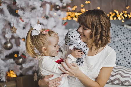 年轻母亲在圣诞节前温柔地拥抱小女孩高清图片