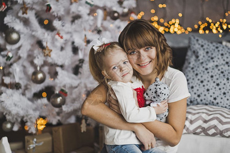 年轻母亲在圣诞节前温柔地拥抱小女孩图片