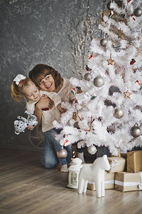 母亲和女儿在圣诞树周围玩得很开心背景图片
