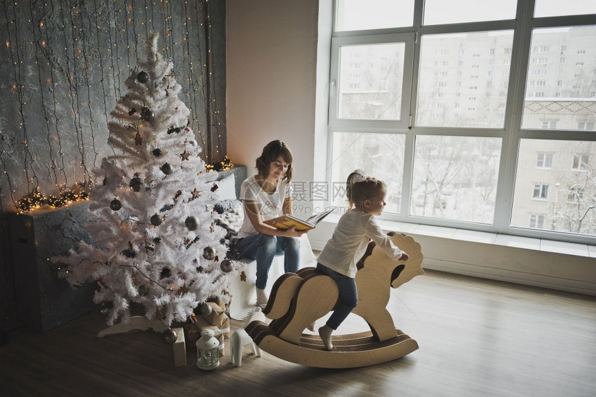女儿和母亲在圣诞树周围玩耍母亲和女儿坐在圣诞树附近7086图片