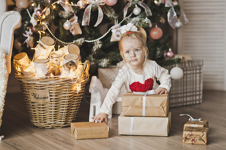 坐在圣诞树下带礼物的小女孩坐在圣诞树旁边的7245号地板上的孩子肖像图片
