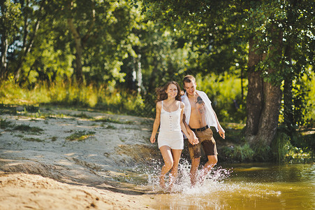 沿着湖边的海滩走一对年轻夫妇沿着水边927行走高清图片