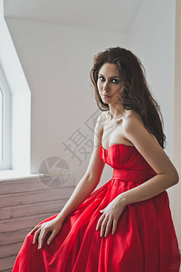 穿着长红色晚礼服的女孩肖像穿着正式礼服的女孩站在窗口602图片