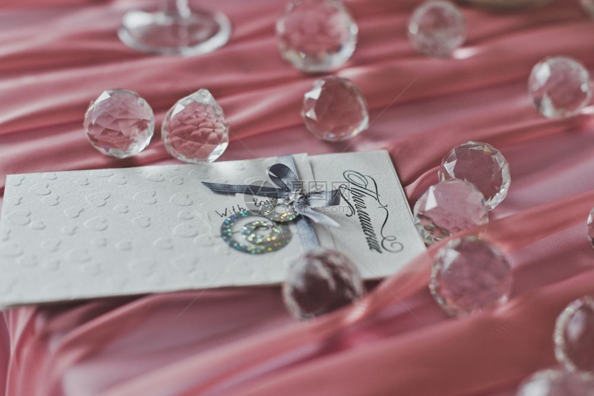 粉色布料上的玻璃球粉色布料上的玻璃球和婚礼邀请函是空白的643图片