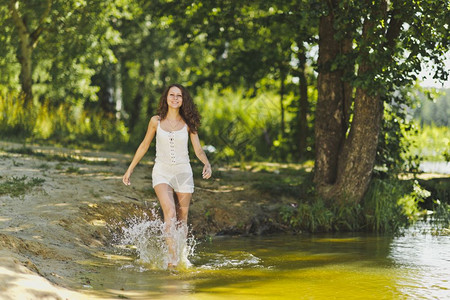 穿白短裙的女孩沿着池塘水边行走图片