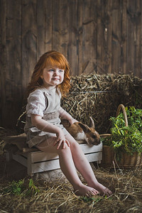 这孩子坐在干草中间的箱子上一个小女孩的肖像在603墙附近的干草里图片
