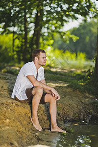 坐在池塘岸边的那家伙坐在海滩6345的年轻人肖像图片