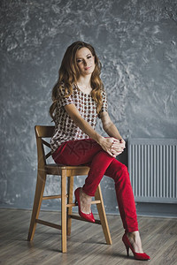 穿红色牛仔裤的年轻女孩坐在椅子上图片