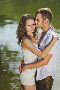 在池塘绿水背景的怀抱中年轻男女拥抱着自然界背景632图片