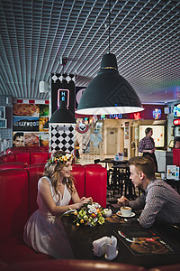 一个男人和女孩坐在咖啡厅的桌子上一个年轻夫妇坐在咖啡厅的587桌图片