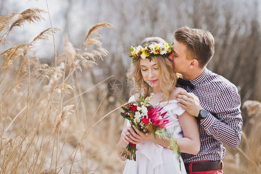 一对年轻夫妇站在草原上亲吻图片