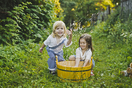 儿童在花园里玩水儿童在475盆地里泼水背景图片