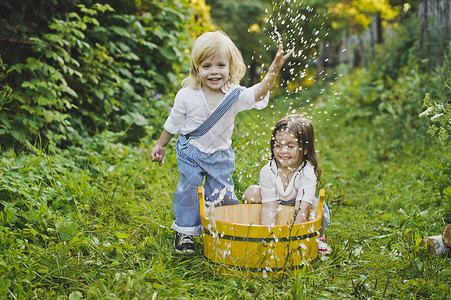儿童在花园里玩水儿童在475盆地里泼水背景图片