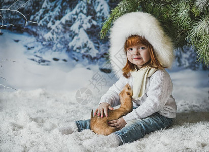 儿童坐在树下的雪中图片