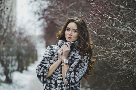穿着毛皮大衣的漂亮女孩在冬季散步图片