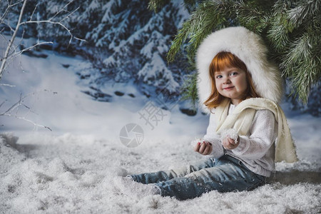 儿童坐在4537树下的雪中图片