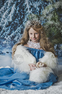 雪公主坐在圣诞树周围的雪里图片