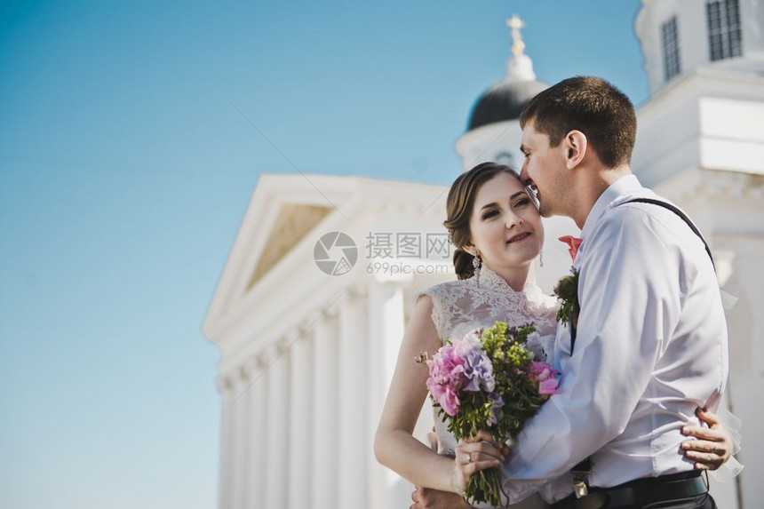 夫妻们站在白柱前丈夫和妻子拥抱着380教堂的背景图片