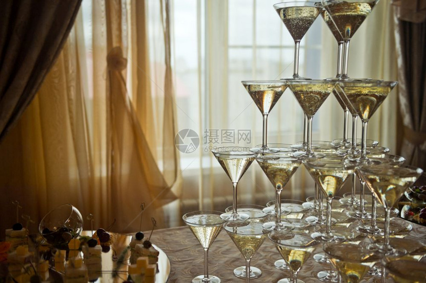 美丽的香槟杯金字塔在光赢的背景上图片