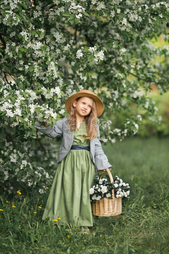 一个小女孩穿过开阔的花园一个穿着简单衣服的小女孩带着一篮子白色紫罗兰1783图片