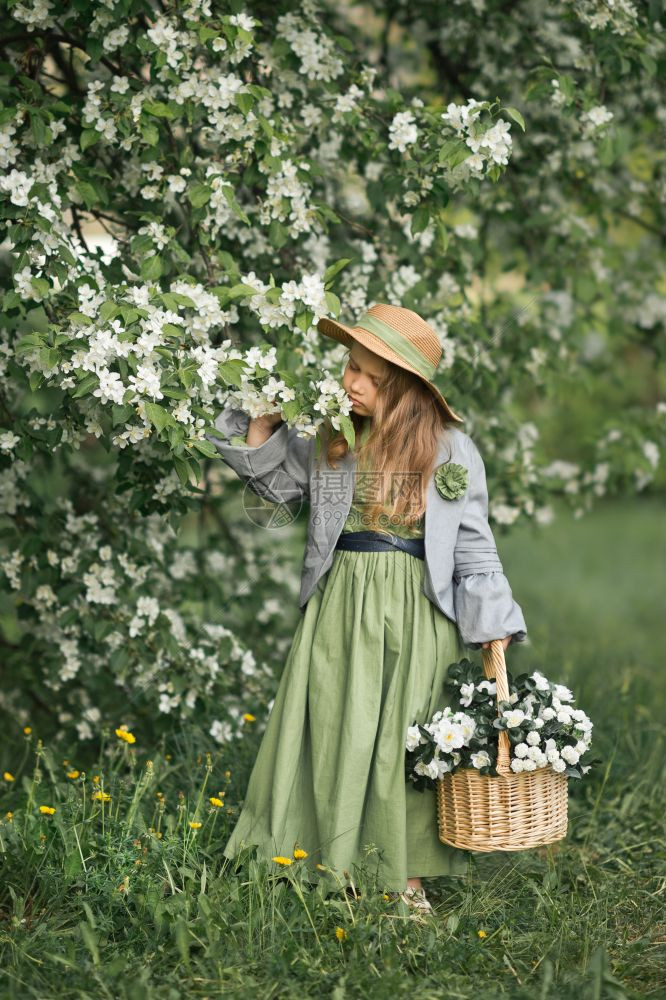 一个小女孩穿过开阔的花园一个穿着简单衣服的小女孩带着一篮子白色紫罗兰1785图片