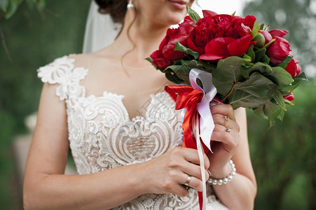 穿着婚纱的新娘手里有一束红色的花284年一个女孩手里有束亮的红色花束图片