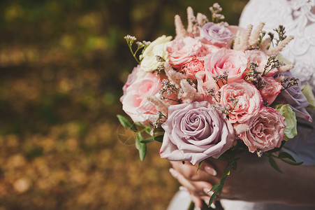 一束白色玫瑰一束鲜花在新娘的手中新娘穿着一件婚礼的镂空白色礼服新娘手持一束鲜花背景