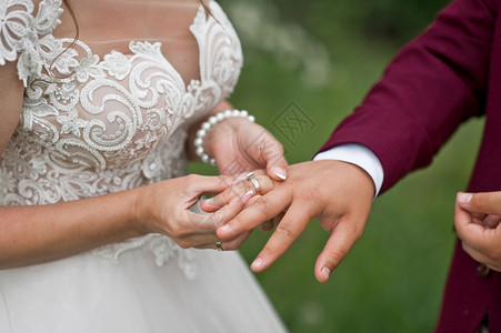 新娘把结婚戒指放在新娘的手上放在绿色背景上图片