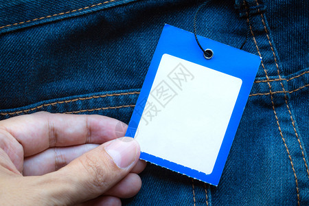 蓝色牛仔裤贴有手持空白标签的蓝色牛仔裤图片