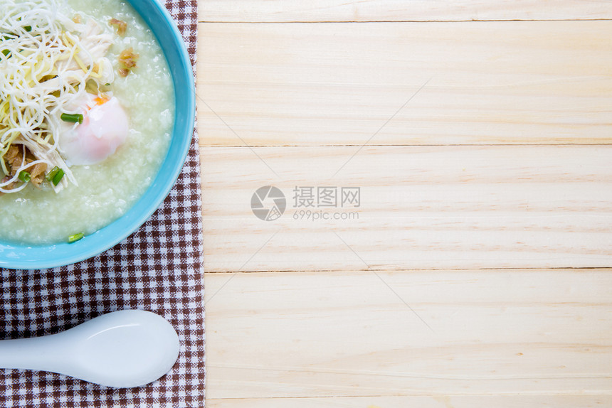 泰国大米粥烧猪肉和木桌上的勺子porkCongee图片