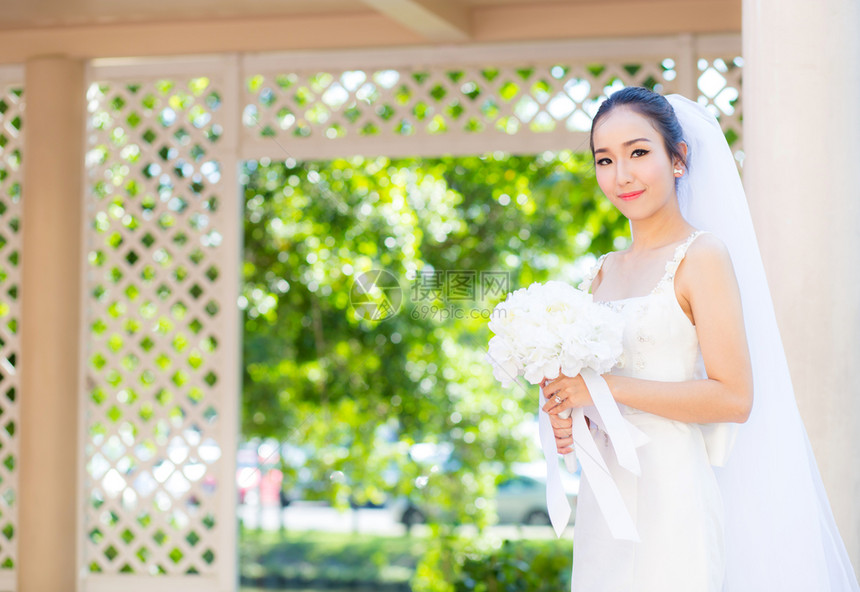 在婚礼当天美丽的年轻女子穿着白色礼服在花园里公的女肖像图片