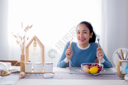漂亮的女人拿着勺子和刀在厨房里微笑图片
