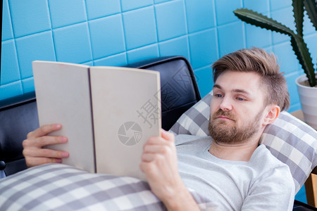 放松男人读一本书写着沙发教育的概念背景图片
